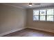 Bedroom features a modern ceiling fan, hardwood floors, neutral walls, and large windows at 7932 Wexford Waters Ln, Wake Forest, NC 27587