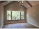 A bedroom boasting vaulted ceilings, large windows, and beautiful hardwood floors offers a serene space at 7932 Wexford Waters Ln, Wake Forest, NC 27587