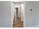 Hallway with hardwood floors, neutral paint, and framed doorways creates inviting transition between rooms at 87 Addison Pond Ct, Zebulon, NC 27597
