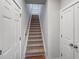 Carpeted staircase ascends between white walls, flanked by paneled doors, enhancing the home's architectural charm at 87 Addison Pond Ct, Zebulon, NC 27597