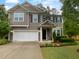 Charming two-story home with gray siding, black shutters, an attached two-car garage, and manicured landscaping at 8844 Forester Ln, Apex, NC 27539