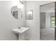 This bathroom features a pedestal sink with a round mirror and modern lighting fixture at 1000 Brighthurst Dr # 104, Raleigh, NC 27605