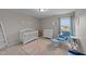 Cozy Bedroom with a white crib, blue rocking chair, a window, and neutral colored walls at 1002 Addington Lake Ln, Knightdale, NC 27545