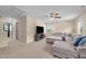 Large living room with a gray sectional sofa, tv, ceiling fan, neutral paint, and carpet flooring at 1002 Addington Lake Ln, Knightdale, NC 27545