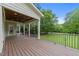 Covered back porch with wooden decking, railings, and views of the backyard and mature trees at 12217 Beestone Ln, Raleigh, NC 27614