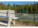 A tennis court with a bench in the foreground and covered gazebos for relaxing in the background at 12217 Beestone Ln, Raleigh, NC 27614
