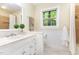 Well-lit bathroom featuring a white vanity, tiled floor, and a window overlooking the trees outside at 12709 Timberlane Ct, Raleigh, NC 27613