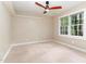 Neutral bedroom with a large window, ceiling fan, and plush carpeting for a cozy feel at 12709 Timberlane Ct, Raleigh, NC 27613