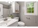 Bathroom featuring white vanity, toilet, window with a wooded view and silver fixtures at 2300 Cowden Ct, Raleigh, NC 27612