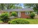 Exterior view of a brick house with a serene backyard, complete with a built-in bench and lush shrubs at 307 Pine Tree Rd, Oxford, NC 27565