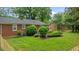 The backyard features a well-maintained lawn, brick home, decorative bushes, and a wooden fence at 307 Pine Tree Rd, Oxford, NC 27565