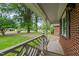 Inviting front porch with brick facade, white railing, and view of a lush green lawn with mature trees at 307 Pine Tree Rd, Oxford, NC 27565