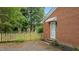 Brick house featuring a side entrance with a vintage awning, fenced yard, and clean landscaping at 307 Pine Tree Rd, Oxford, NC 27565