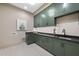 Laundry room with custom green cabinetry, a dark countertop, and white patterned tile flooring at 3407 Churchill Rd, Raleigh, NC 27607