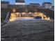 Backyard patio featuring a stylish stone fire pit with built-in seating and outdoor lighting at 400 Access Dr, Youngsville, NC 27596