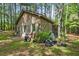 A backyard outbuilding with a rustic vibe is surrounded by mature trees and landscaping at 4501 Zebulon Rd, Zebulon, NC 27597