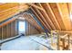 Unfinished attic space with exposed rafters, a window, and blue insulation at 540 W Juniper Ave, Wake Forest, NC 27587