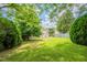 Large, grassy backyard surrounded by lush trees, hedges, and a wood fence at 5522 Marthonna Way, Raleigh, NC 27616