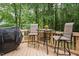 Back deck features seating and a grill with views of the lush green backyard at 5629 Yates Garden Ln, Raleigh, NC 27606