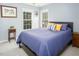 Bedroom features two windows, a queen bed, a small plant stand, and blue walls at 5629 Yates Garden Ln, Raleigh, NC 27606