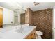 Brick walled bathroom with large mirror, tile counters, and standard toilet at 612 Greenwood Rd, Chapel Hill, NC 27514