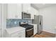 Modern kitchen with white cabinets, stainless steel appliances, and blue hexagon tile backsplash at 713 Chandler Stone Dr, Zebulon, NC 27597