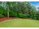 Well-manicured backyard featuring a lush lawn, trees, and mulch bed at 802 Windermere Lake Ct, Apex, NC 27502