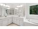 Bright bathroom with tub, vanity, sinks, and large mirror at 802 Windermere Lake Ct, Apex, NC 27502