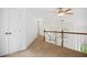 Upstairs hallway featuring neutral carpet, white walls, and natural wood banister at 802 Windermere Lake Ct, Apex, NC 27502