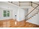 Spacious living room with hardwood floors, staircase, and a window with natural light at 802 Windermere Lake Ct, Apex, NC 27502