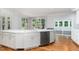 Bright kitchen features white cabinetry, stainless appliances, sleek countertops, and beautiful hardwood floors at 90021 Hoey, Chapel Hill, NC 27517