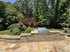 Stone outdoor kitchen with a built-in grill, stone countertops, and patio overlooking a landscaped backyard at 90021 Hoey, Chapel Hill, NC 27517