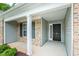 Inviting entryway featuring a covered porch with brick accents and a stylish black front door at 905 Alice Ct, Haw River, NC 27258
