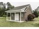 Outbuilding featuring brick construction, a covered porch with columns, and a manicured lawn at 9123 Thomas Rd, Rocky Mount, NC 27803