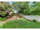 Grassy backyard featuring mulched landscaping, mature trees, and a charming white fence at 9639 Clubvalley Way, Raleigh, NC 27617