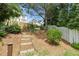 Wooded backyard with brick steps leading to a garden area with a white picket fence and mature trees at 9639 Clubvalley Way, Raleigh, NC 27617
