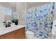 Bathroom with tan cabinets, white sink, toilet, floral shower curtain and neutral wall color at 9639 Clubvalley Way, Raleigh, NC 27617