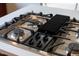 Close up of the kitchen island's gas cooktop, with black grates at 9639 Clubvalley Way, Raleigh, NC 27617