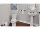 Well-lit half bathroom with hardwood floors, a modern pedestal sink, and neutral paint at 9639 Clubvalley Way, Raleigh, NC 27617
