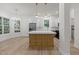 A well-lit kitchen with wooden floors, stainless steel appliances and large kitchen island with quartz countertop at 100 Citrus Pl, Cary, NC 27519