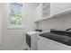 Well-lit laundry room with white cabinets, window and modern, front loading machines at 100 Citrus Pl, Cary, NC 27519