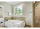 Bathroom with a large tub, a window with backyard view and a glass enclosed shower at 108 Ellsworth Pl, Chapel Hill, NC 27516