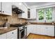 Bright kitchen featuring stainless steel appliances, stone countertops, and white cabinetry at 108 Ellsworth Pl, Chapel Hill, NC 27516