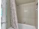 Bathtub with a tile shower and a neutral colored shower curtain in a well lit bathroom at 10909 Raven Rock Dr, Raleigh, NC 27614