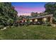 Brick home featuring a spacious deck and lush, landscaped yard at dusk at 10909 Raven Rock Dr, Raleigh, NC 27614