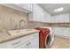 Efficient laundry room boasting ample cabinet space, tiled backsplash, and side-by-side washer and dryer units at 10909 Raven Rock Dr, Raleigh, NC 27614