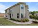 Corner-unit tan townhome showcasing an attached garage, stone accents, and lush landscaping at 1136 Longitude Dr, Durham, NC 27713