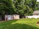 Spacious backyard with lush grass, storage sheds, landscaping, and mature trees at 1290 Pyrtle Dr, Graham, NC 27253