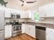 Bright kitchen featuring stainless steel appliances, white cabinets, and a window overlooking the backyard at 1290 Pyrtle Dr, Graham, NC 27253