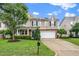 Attractive two-story home with a well-manicured lawn, mature tree, and stone accents on the facade at 149 Cinder Cross Way, Garner, NC 27529